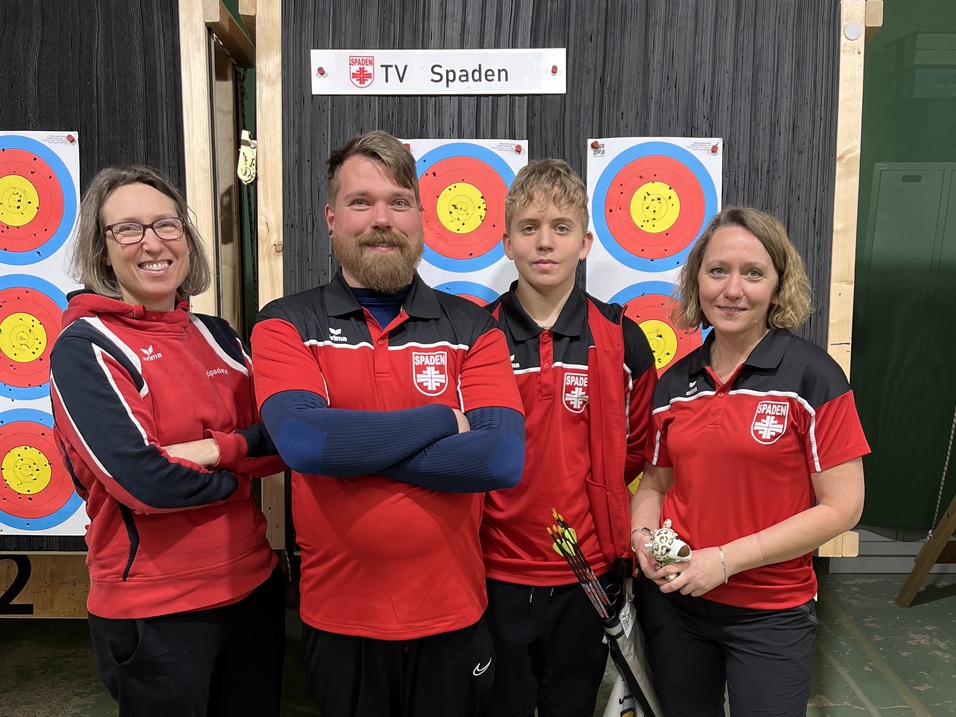 Vier Sportler in roten Team-Shirts stehen vor einer Zielscheibe. Hinter ihnen sind verschiedene Zielscheiben und ein Schild &bdquo;TV Spaden&ldquo;.