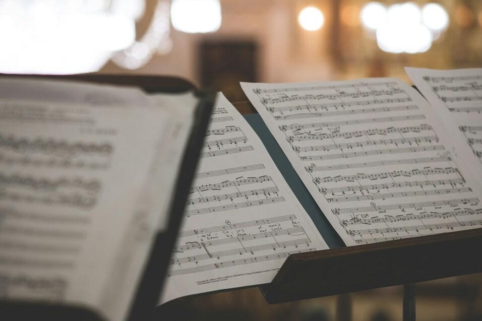 Notenblätter mit musikalischer Schrift auf einem Notenständer in einem hell erleuchteten Raum.