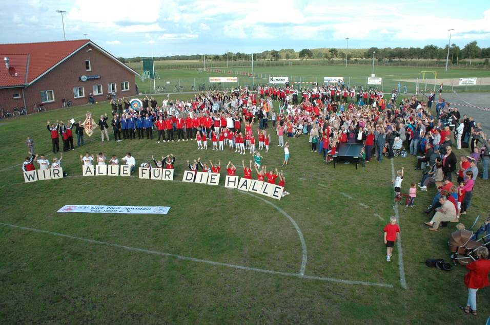 Gro&szlig;e Menschenmenge auf einem Sportplatz h&auml;lt ein Banner mit der Aufschrift &bdquo;WIR ALLE F&Uuml;R DIE HALLE&ldquo;.