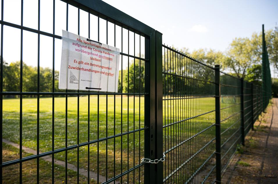 Sicht auf einen geschlossenen Sportplatz mit einem Schild, das auf ein Betretungsverbot aufgrund der Corona-Pandemie hinweist.