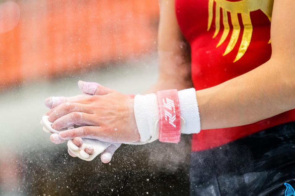 Nahaufnahme von Händen eines Turners mit Chalk, die vor einem Wettkampf im Gymnastik bereitgemacht werden.